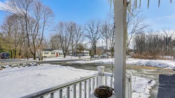 A residential area with a snow-covered driveway, a white railing, and a house in the background.