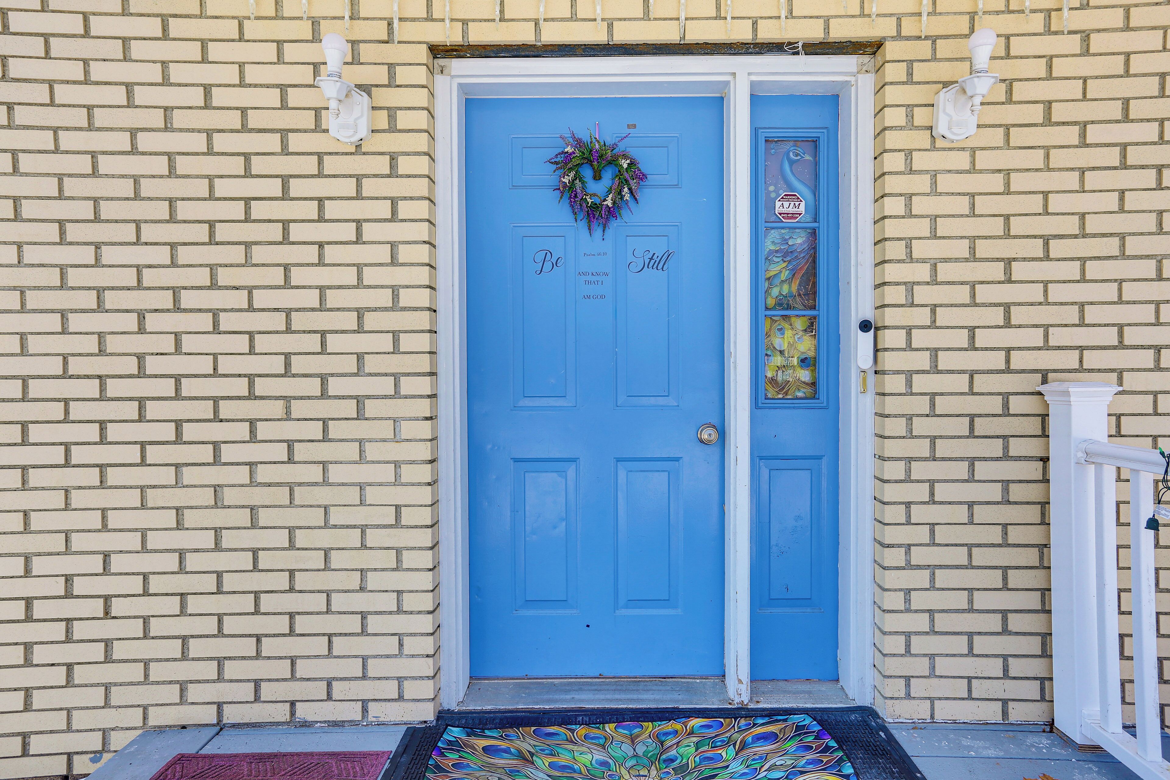 A blue door with a wreath, a stop sign, and a doormat.