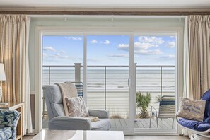 A balcony with a view of the ocean, a grey sofa, and a chair with a cushion. - *Fall into Savings-20% Off New Bookings thru 2026* (Myrtle Beach)