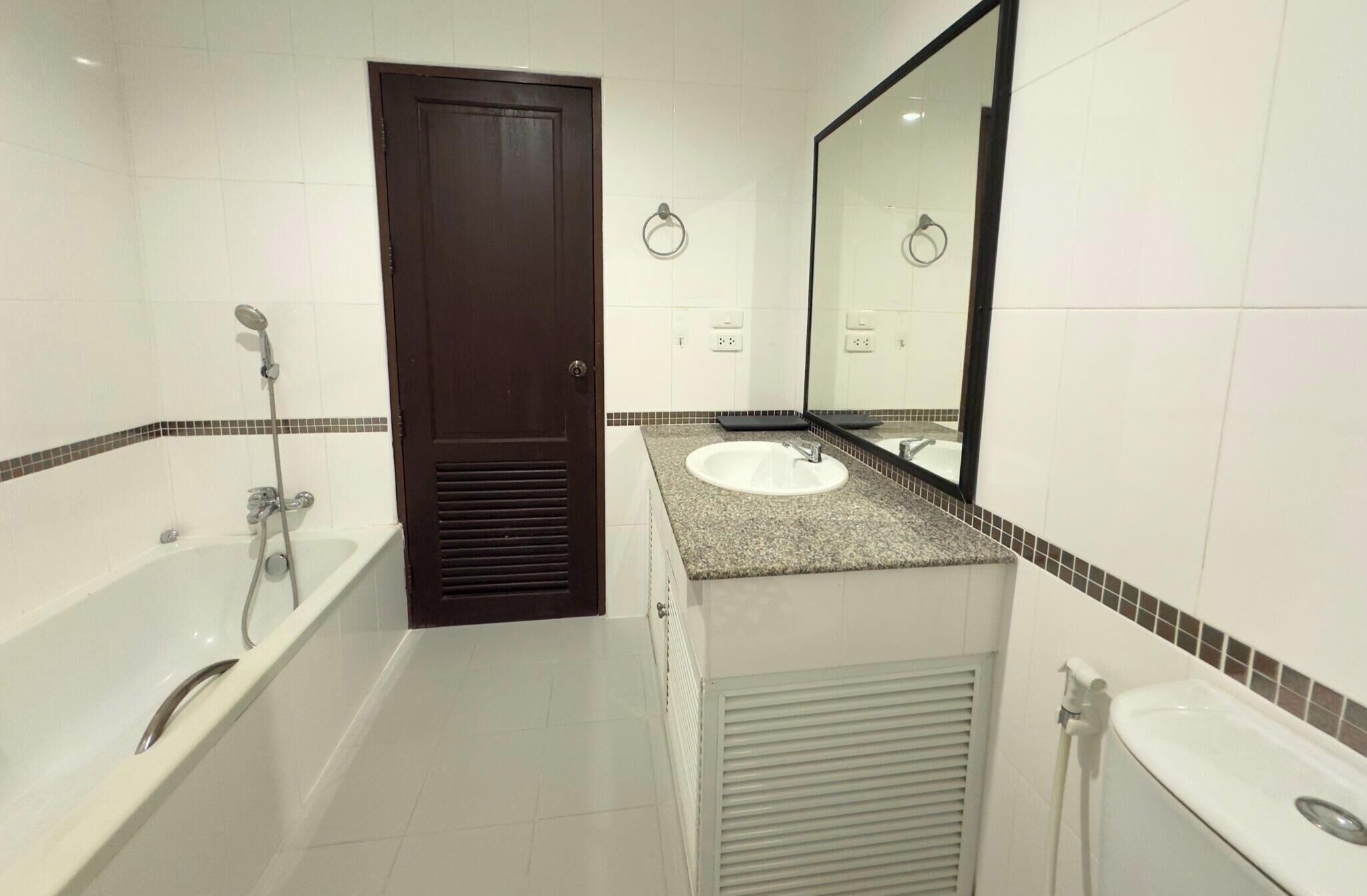 A modern bathroom with a bathtub, a sink, and a mirror.