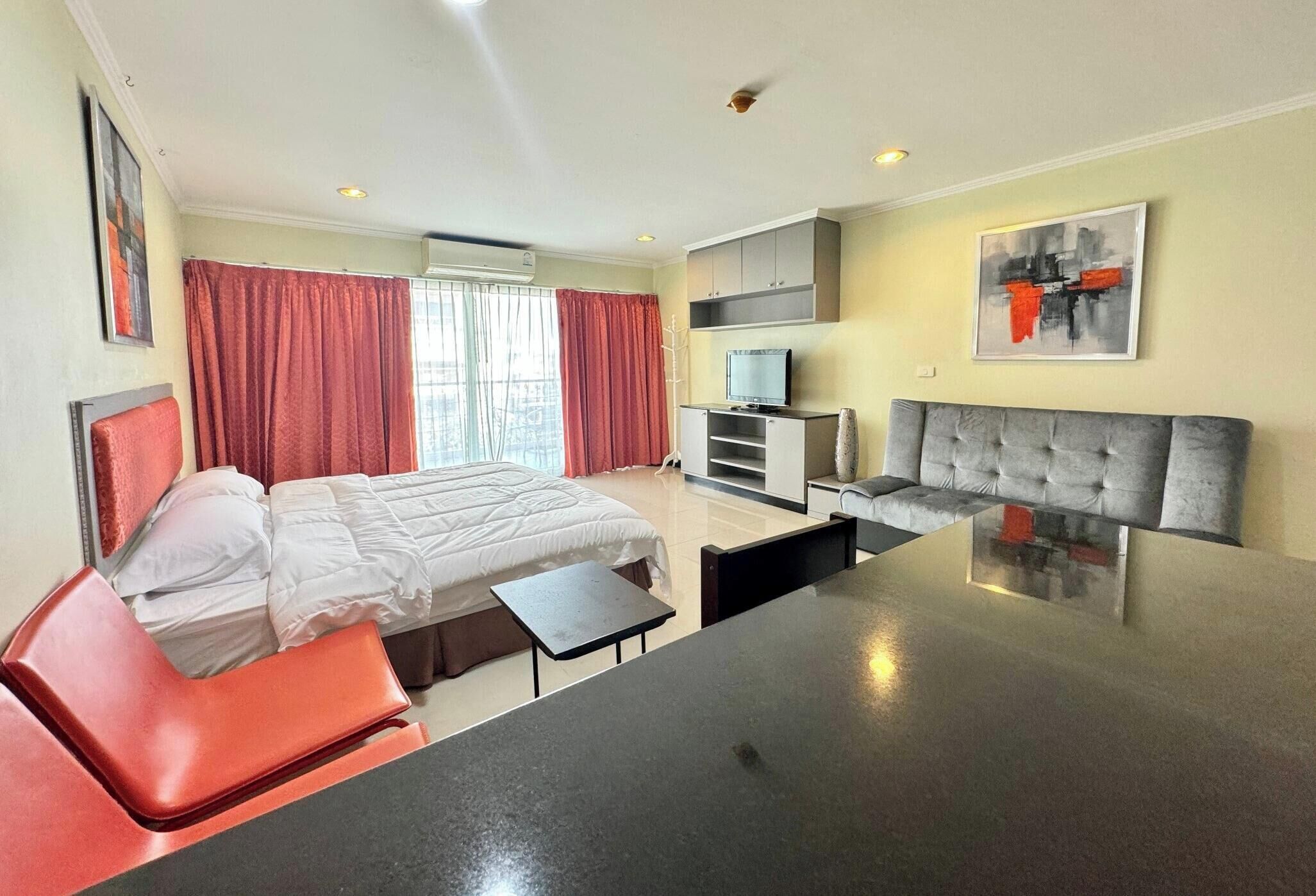 Una habitación de hotel con cama, sofá, televisión y mesa de comedor.