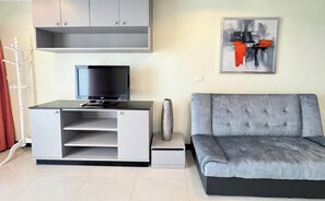 Ein modernes Wohnzimmer mit einem grauen Sofa, einem Flachbildfernseher auf einer weißen Unterhaltungsanlage und einem modernen abstrakten Gemälde an der Wand.
