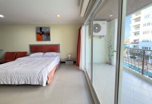 Ein Hotelzimmer mit einem großen Bett, einem Nachttisch, einer Wand-Klimaanlage und Blick auf den Außenbalkon.