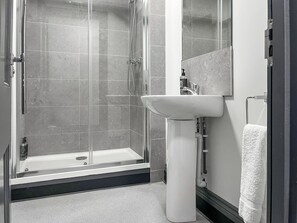 Une salle de bain moderne avec une douche à parois de verre, un lavabo sur pied blanc et un porte-serviettes.
