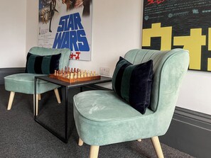 Une pièce avec deux fauteuils verts, un jeu d’échecs et une affiche de Star Wars.