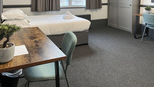 A hotel room with a bed, a desk, a chair, a wardrobe, and a window with curtains. - 8 bedroom accommodation in Sunderland (Sunderland)