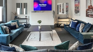 A modern living room with two sofas, a coffee table, a TV, and framed movie posters on the wall. - 8 bedroom accommodation in Sunderland (Sunderland)