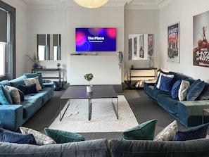 A modern living room with two sofas, a coffee table, a TV, and framed movie posters on the wall. - 8 bedroom accommodation in Sunderland (Sunderland)