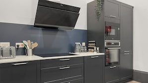 A modern kitchen with a built-in microwave, oven, and a flat-screen TV above the counter. - 8 bedroom accommodation in Sunderland (Sunderland)