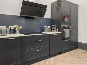 A modern kitchen with a built-in microwave, oven, and a flat-screen TV above the counter. - 8 bedroom accommodation in Sunderland (Sunderland)
