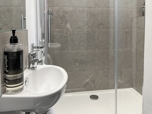 A bathroom with a white sink, a glass shower enclosure, and a bottle of hand soap. - 8 bedroom accommodation in Sunderland (Sunderland)