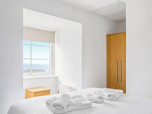 Une chambre d’hôtel avec un lit, une table de chevet en bois, un radiateur, une armoire et une fenêtre donnant sur un paysage agréable.