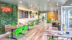 Een café met groene stoelen, een neonbord, een menukaart en een houten wand.