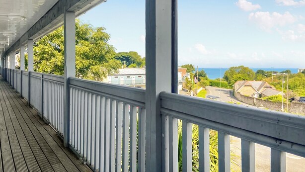 Ein überdachter Außenbereich mit Blick auf das Meer und Gebäude.