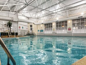 An indoor swimming pool with clear water, a metal ladder, and safety signs on the walls. - 5T Monk's Rock - UKC8995 (Illfracombe)