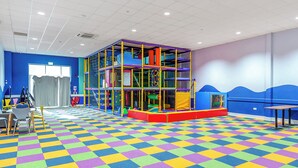 A play area with a colorful checkered floor, a play structure, and seating.