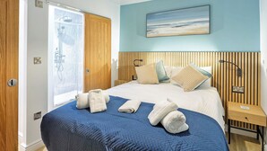 Una camera da letto con un letto, una testiera in legno, un quadro, un comodino e un bagno con doccia.