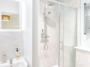 A modern bathroom with a glass-enclosed shower, a white sink, and a mirror. - 178 Residences - UKC8998 (Illfracombe)
