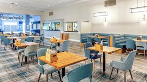 A modern hotel lobby with multiple seating areas, a reception desk, and a visible kitchen area. - 177 Residences - UKC8999 (Illfracombe)