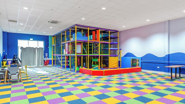 A play area with a colorful checkered floor, a play structure, and seating. - 177 Residences - UKC8999 (Illfracombe)