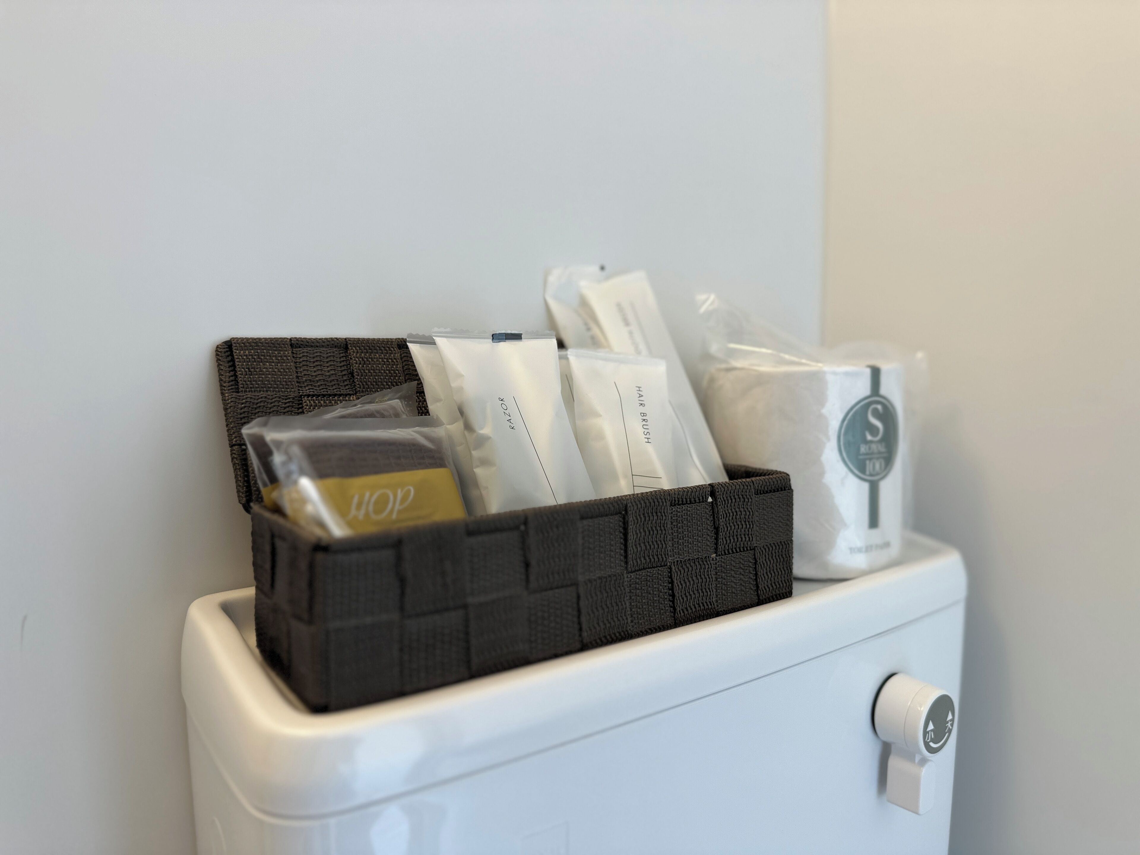 A bathroom with a black storage basket containing toiletries and a white toilet.