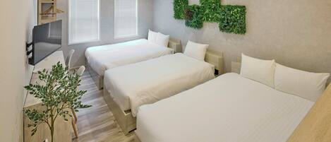A hotel room with two beds, a TV, a plant, and a wall-mounted green wall decoration.