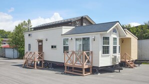 A small, single-story mobile home with a gabled roof, a front porch, and a small attached garage. - Solana Smart INN Fuji Yamanakako (Yamanakako)