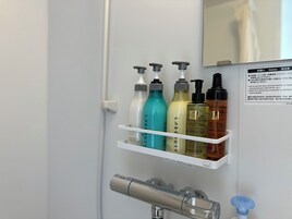 A bathroom with a white shelf holding various toiletries, a mirror, and a faucet.