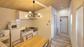 A modern kitchen with white cabinets, a wooden dining table, and a built-in microwave. - Solana Smart INN Fuji Yamanakako (Yamanakako)