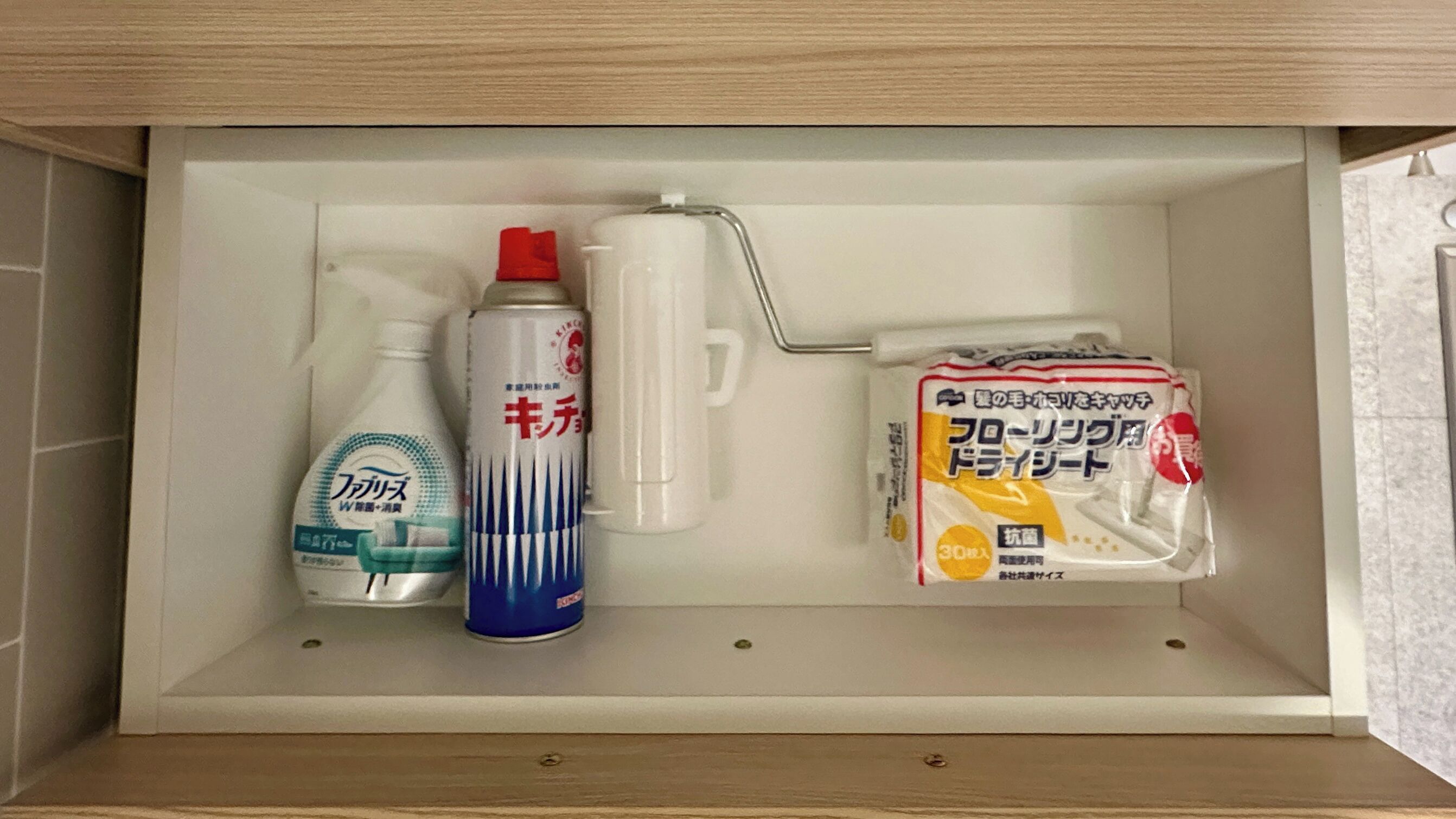 Un estante de baño con una botella de jabón líquido, un ambientador en aerosol, un pulverizador y un paquete de papel higiénico.