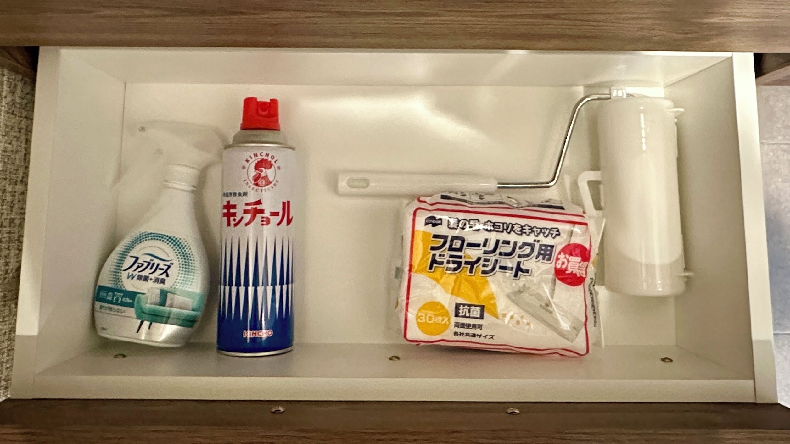 A bathroom with a white sink, a bottle of hand soap, a spray bottle, and a paint roller.