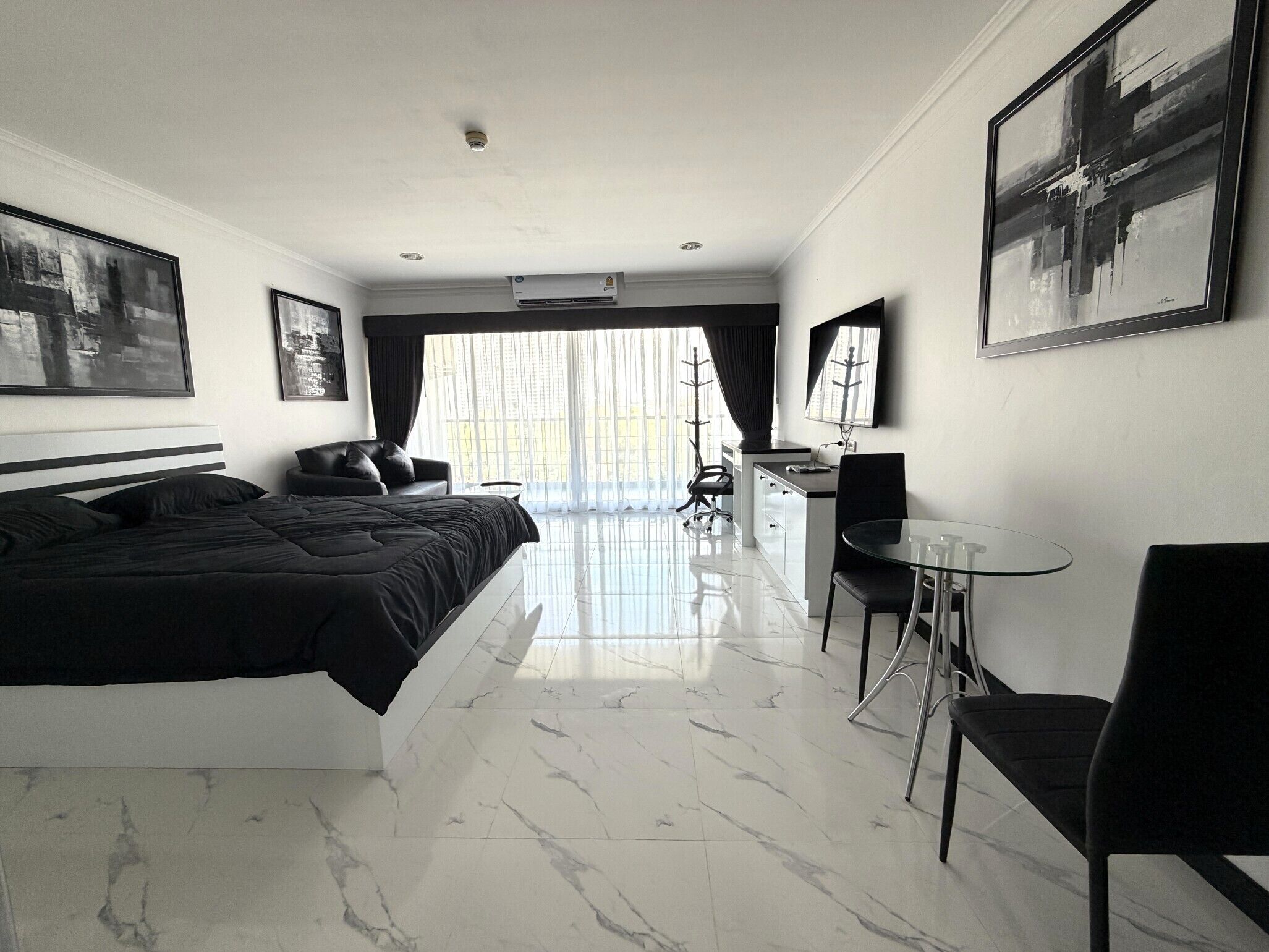 A modern hotel room with a large bed, a desk, and a chair.