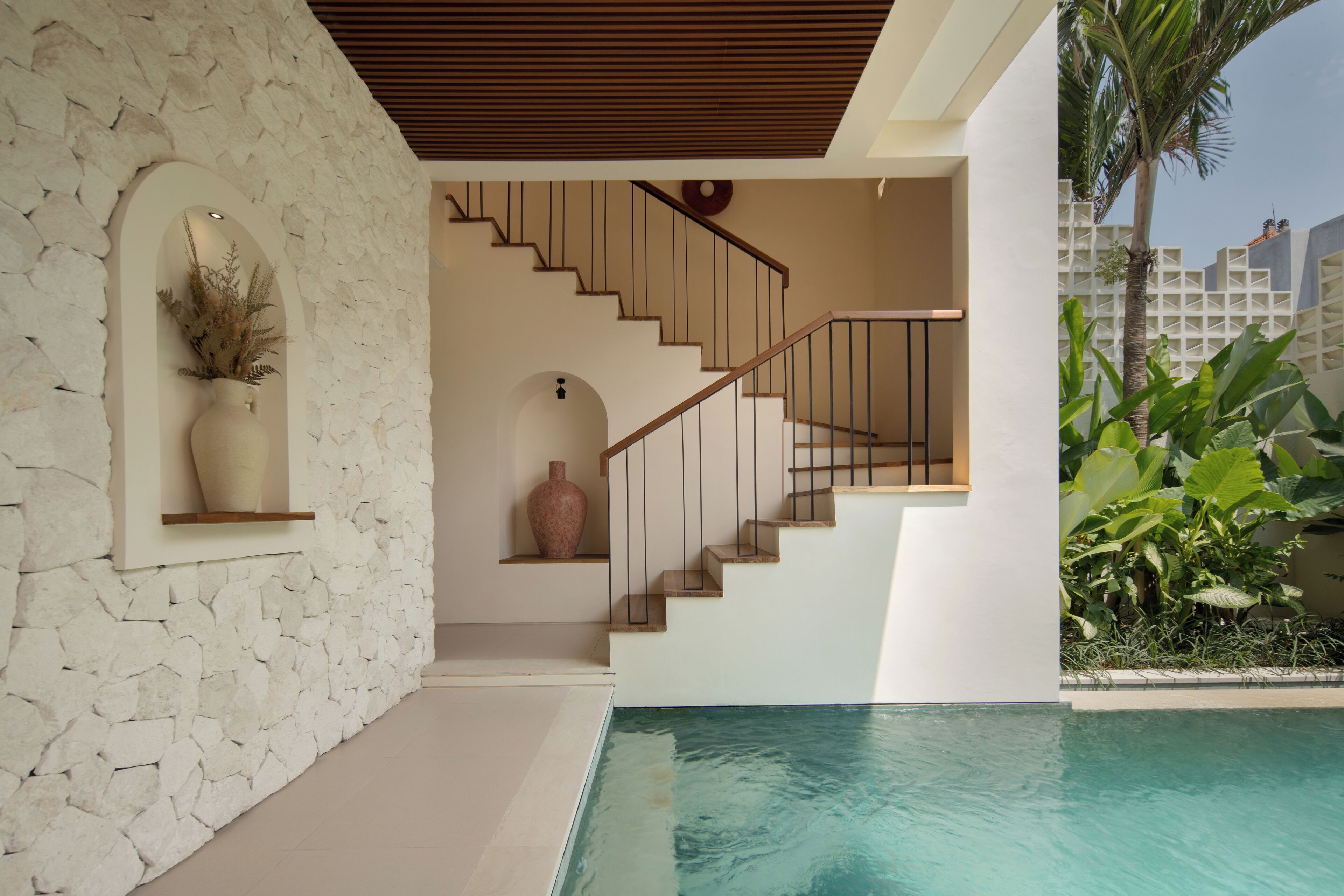 Un intérieur moderne avec un mur en pierre, un escalier et un espace piscine.