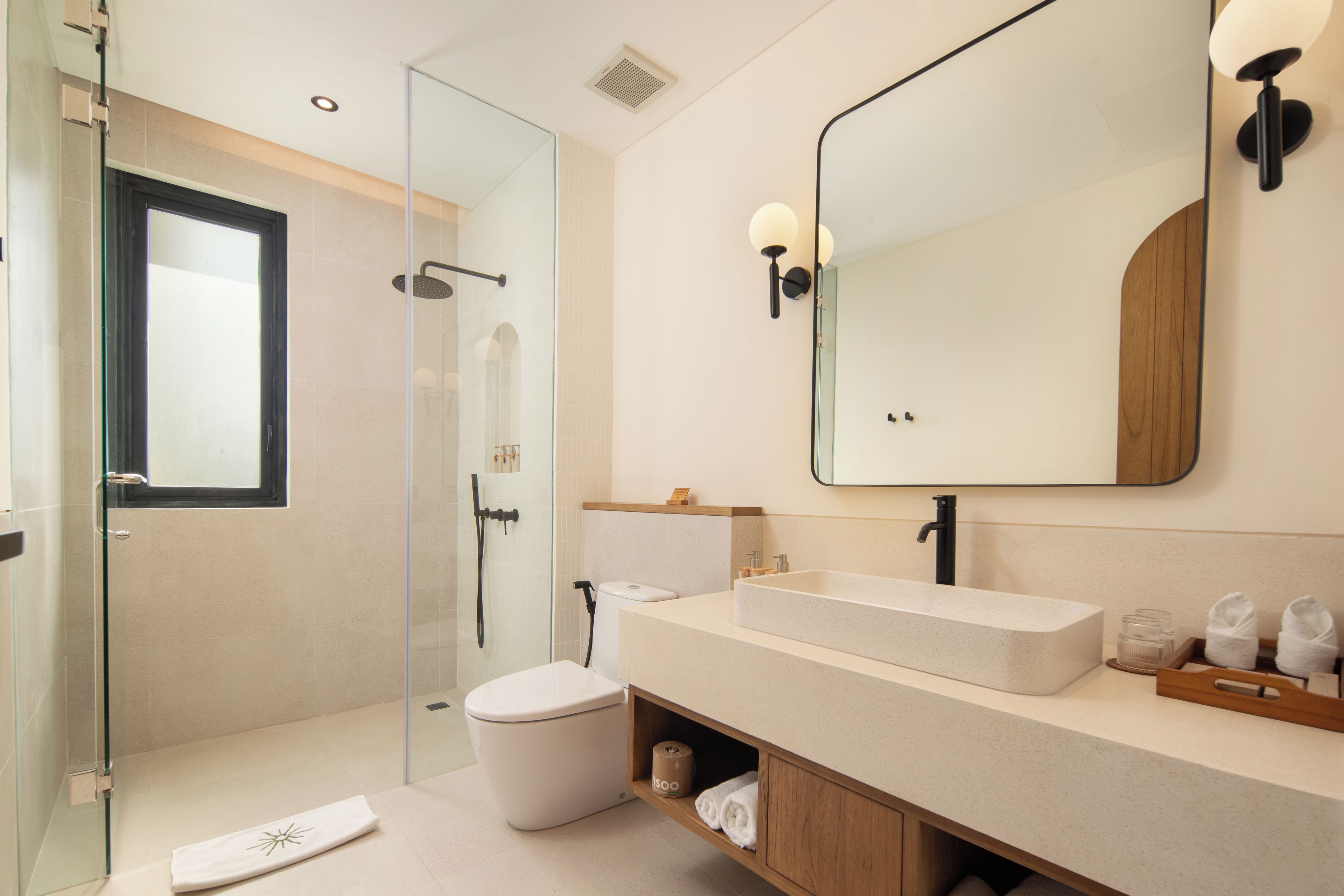A modern bathroom with a glass shower enclosure, a white toilet, a freestanding sink, and a large mirror.