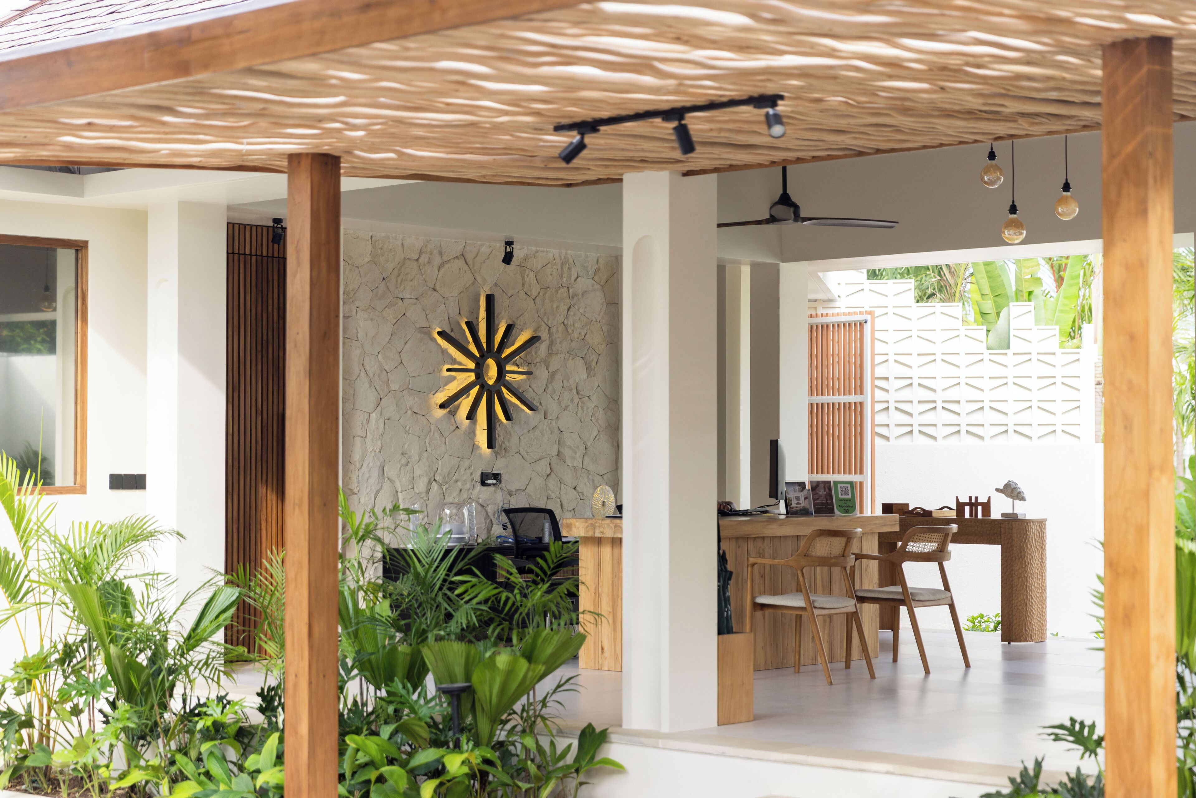 Un intérieur moderne avec un mur en pierre, des meubles en bois et un ventilateur de plafond.