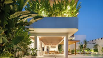 A modern multi-level residential building with a pool and outdoor seating area.