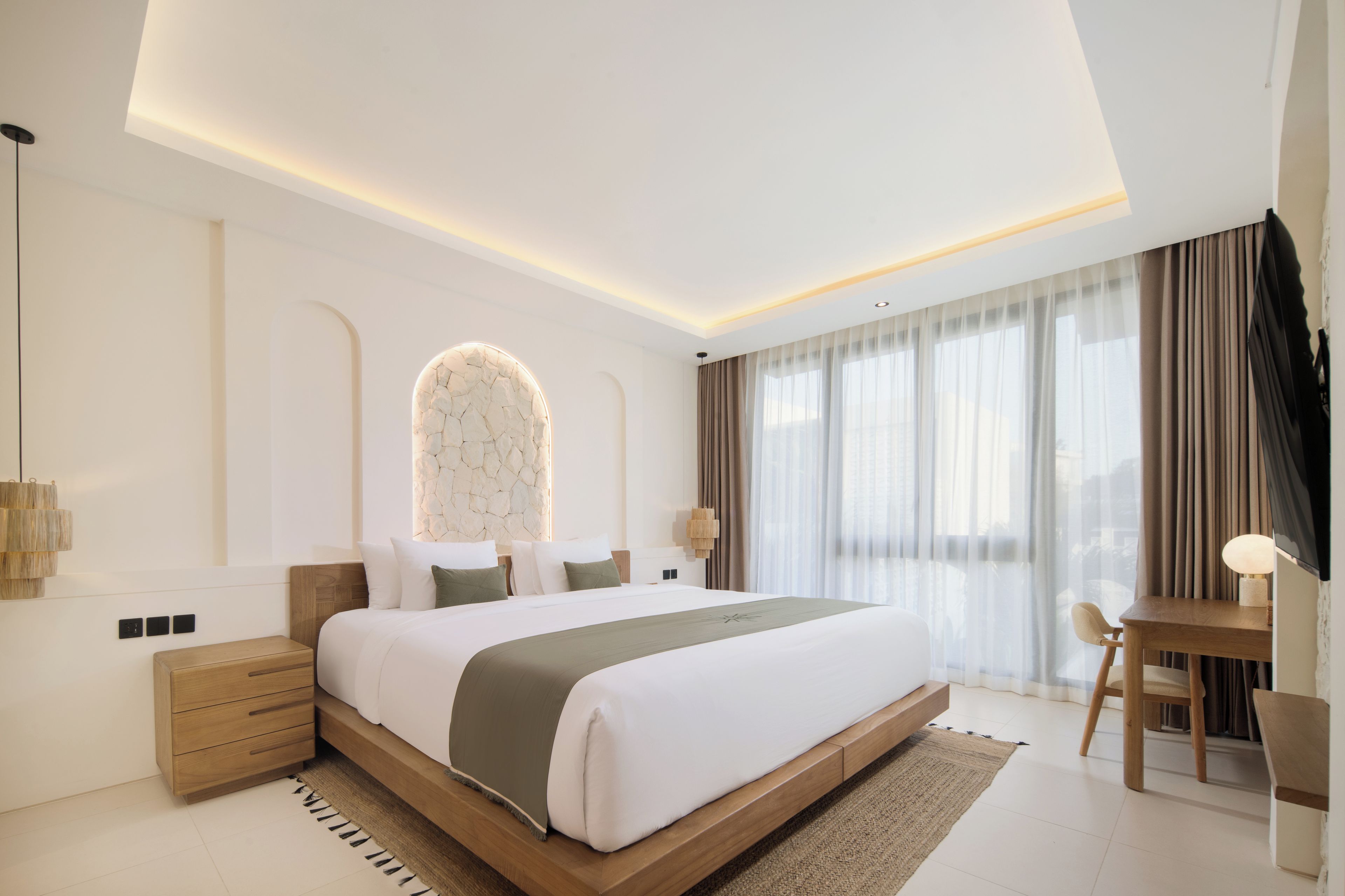 A modern bedroom with a large bed, bedside tables, a desk, and a chair.