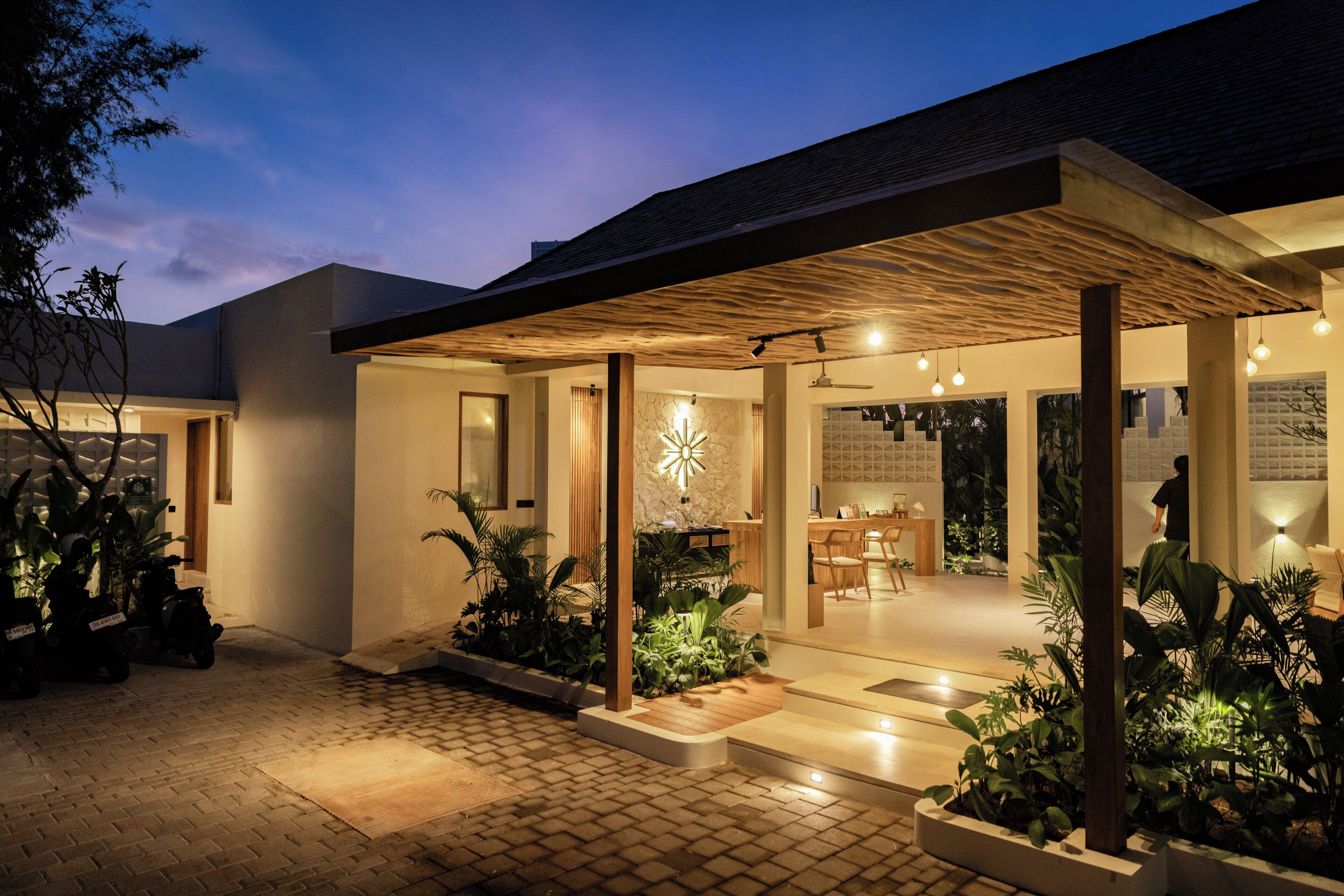 A modern house with a covered patio, indoor lighting, and a dining area.