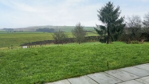 Un campo cubierto de hierba con un muro de piedra y árboles.