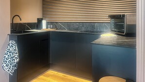 Una cocina moderna con armarios negros, protector contra salpicaduras de madera y horno empotrado.