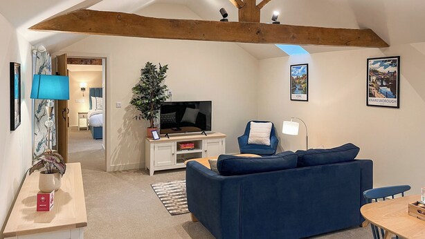 Uma sala de estar moderna com um sofá azul, uma televisão e um vigário de madeira no teto.