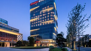 A modern hotel with a prominent sign, multiple floors, and a well-lit facade. - Hampton by Hilton Hangzhou Xiaoshan Jiangnan Technology City. (Hangzhou)
