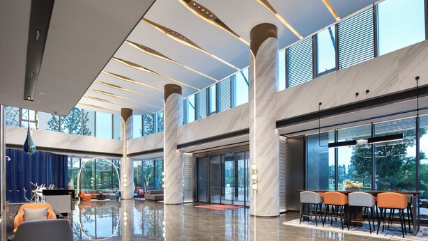 A spacious lobby with a polished floor, large windows, and a seating area with chairs and tables. - Hampton by Hilton Hangzhou Xiaoshan Jiangnan Technology City. (Hangzhou)