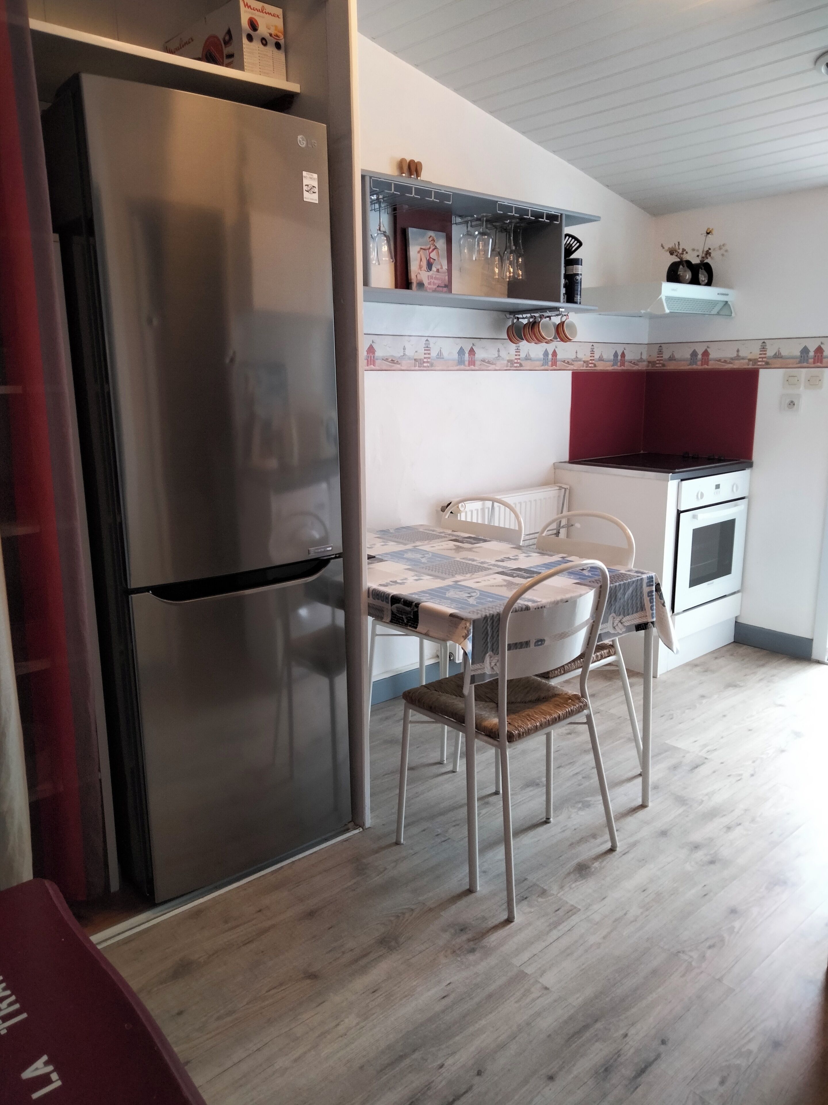 Una cocina compacta con refrigerador de acero inoxidable, estufa blanca y una mesa de comedor con dos sillas.