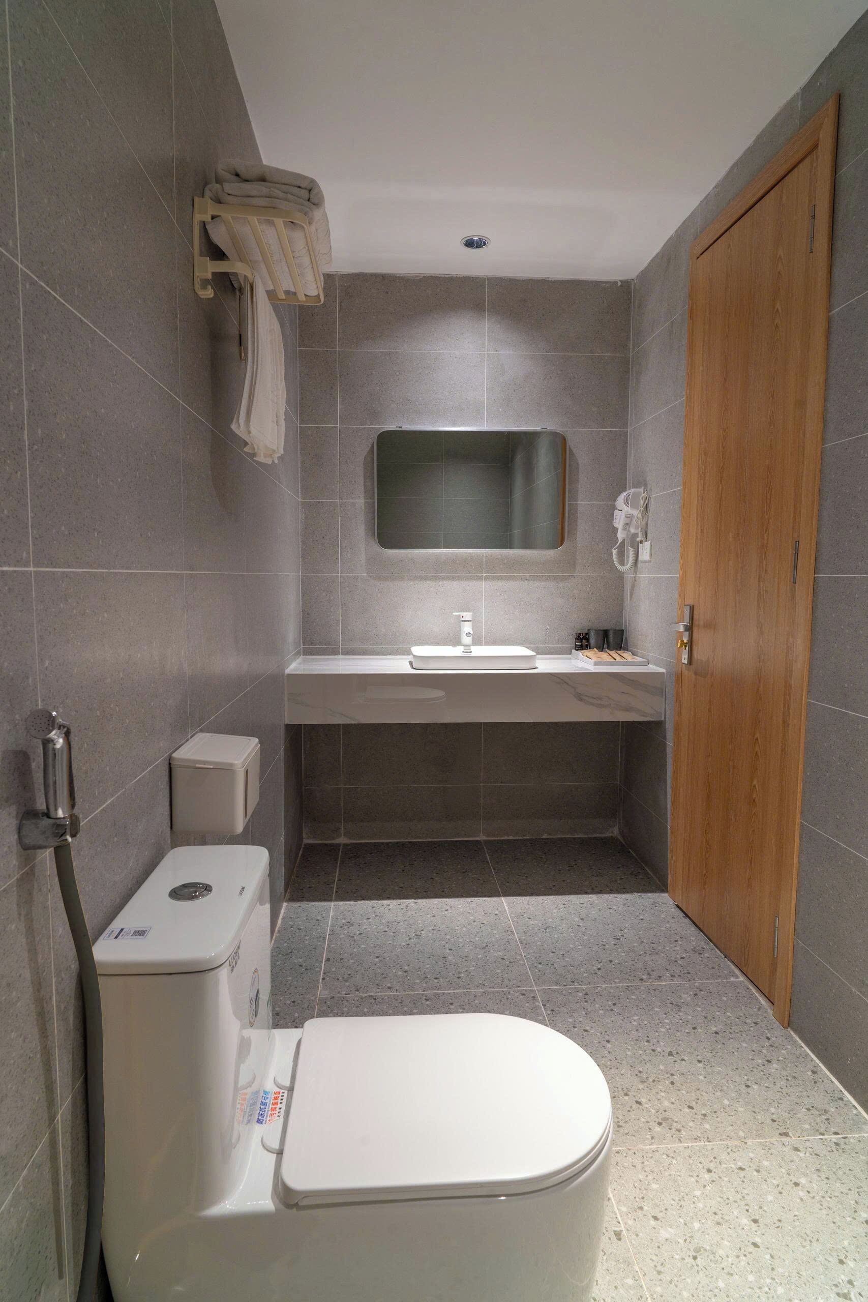A compact bathroom with a toilet, sink, and mirror.