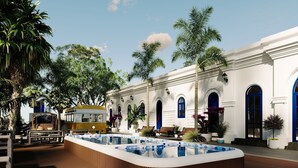 Ein Innenhof mit Pool, Sitzgelegenheiten im Freien und einem weißen Gebäude mit blauen Türen.