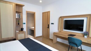 Ein modernes Hotelzimmer mit einem Bett, einem Schreibtisch mit Stuhl, einem Fernseher und einem Kleiderschrank.