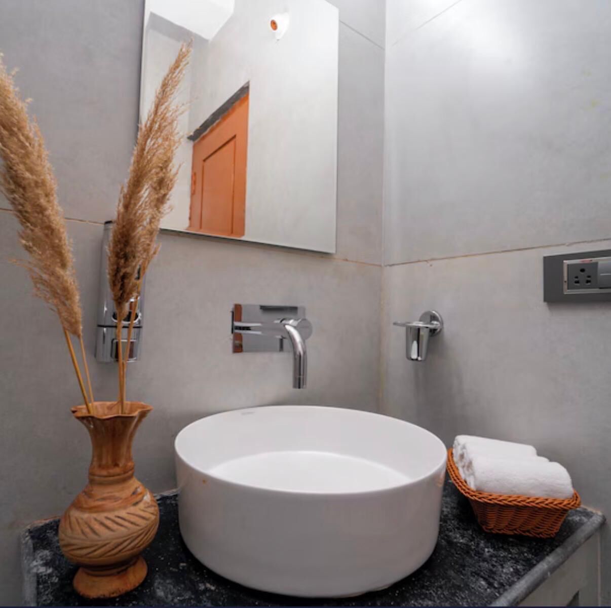 Une salle de bain avec un lavabo rond blanc, un miroir et un porte-serviettes.