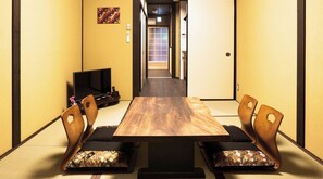 Una stanza tradizionale giapponese con pavimenti in tatami, un tavolino basso e pareti con schermi shoji.
