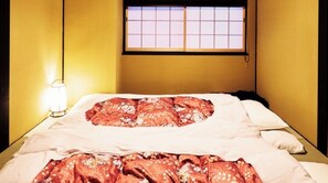 Una stanza con un letto, un comodino con una lampada e una finestra con inferriate.